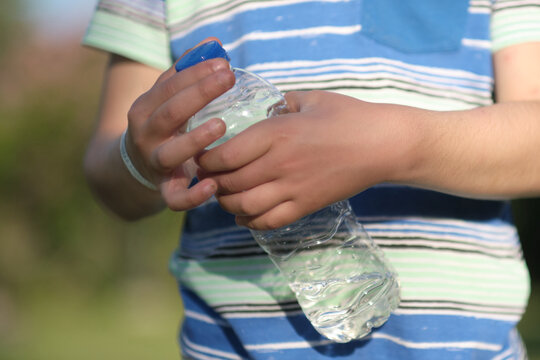 unrecognizable boy holding a bottle of clean water in his hands. the concept of using and recycling platik