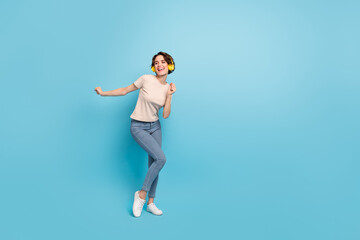 Fototapeta na wymiar Photo of pretty cute lady dressed beige t-shirt earphones dancing empty space isolated blue color background