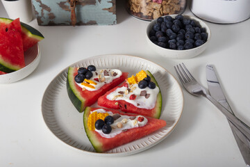 sliced watermelon with cheese cream, berries, nuts and muesli as a summer breakfast or snack