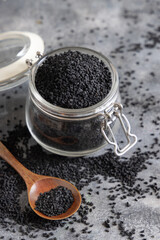 Fototapeta na wymiar Indian spice Black cumin (nigella sativa or kalonji) seeds in glass jar with a wooden spoon close up