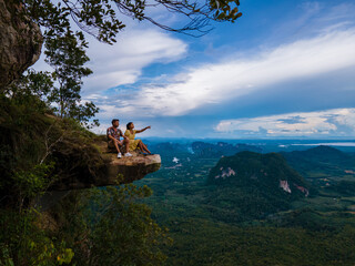 Dragon Crest mountain Krabi Thailand, a Young traveler sits on a rock that overhangs the abyss,...