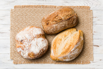 Naklejka premium Assortment of freshly baked bread with napkin on rustic table top view. Healthy unleavened bread. French bread