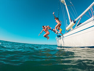 Happy friends diving from sailing boat into the sea - Focus on left girl face