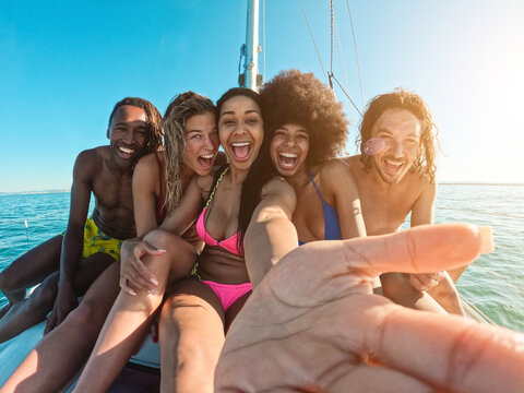 Happy multiracial friends taking a selfie while doing sea tour with sailing boat - Powered by Adobe