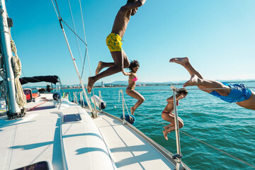 Happy friends diving from sailing boat into the sea - Focus on left girl face right man face -...