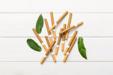 Menthol cigarettes and fresh mint leaves on colored background, Many cigarettes stacked together...