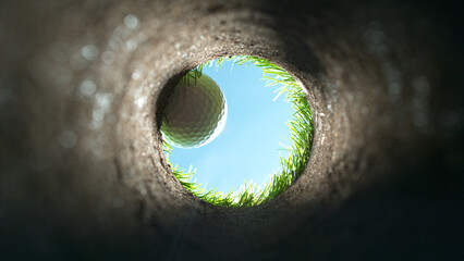 Super slow motion of golf ball falls into the hole at the camera, view inside the hole close-up. - obrazy, fototapety, plakaty