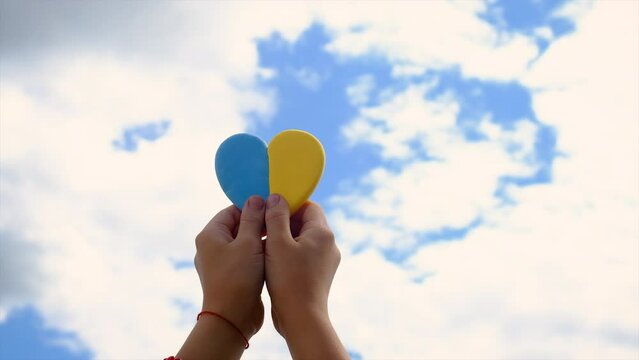 A child holds the heart of Ukraine the sky. Selective focus.