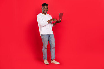 Full body photo of positive person hold use wireless netbook isolated on red color background