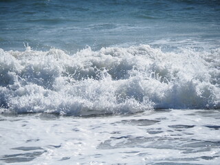 Fototapeta premium White bubbling water as waves are crushing on blue ocean.