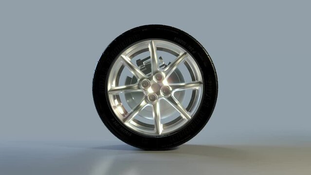 Side on view of a 3D wheel rolling across the screen. Standard black, rubber tyre and wheel rim in a continuous spin. Footage with a luma matte for isolating the object.