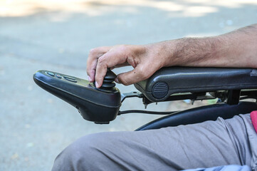 A person with a disability operates a wheelchair. Man using joystick to drive electric wheelchair, close up.  © Ajdin Kamber