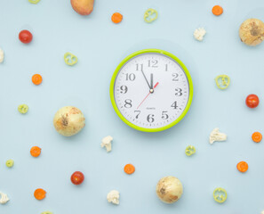 Green clock surrounded with fresh vegetables. Time for healthy eating concept.