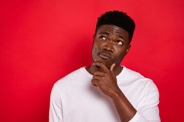 Portrait of minded intelligent person hand chin look interested empty space isolated on red color background