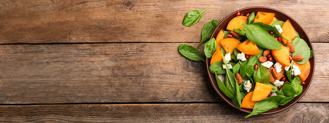Delicious persimmon salad served on wooden table, top view with space for text. Banner design