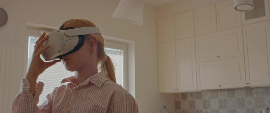 Pre teen girl putting on 360 VR headset at home, starting a virtual reality game. Shot with 2x anamorphic lens