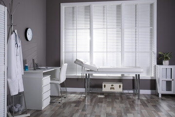 Modern medical office interior with doctor's workplace and examination table