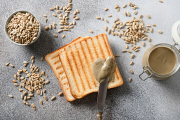 Crispy bread with homemade Sunflower seed butter on gray background. Cooking vegan breakfast. View from above. Alternative for nut butter.