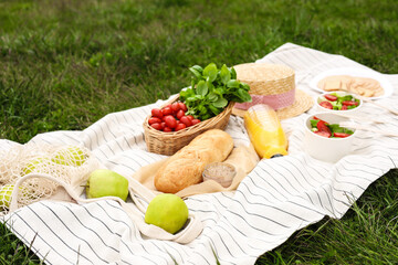 Picnic blanket with juice and food on green grass