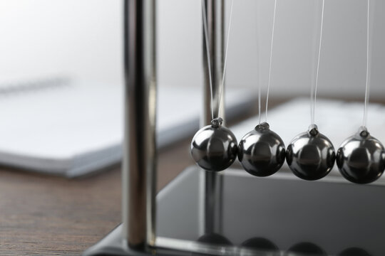 Newton's Cradle On Wooden Table, Closeup. Physics Law Of Energy Conservation