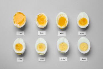 Different cooking time and readiness stages of boiled chicken eggs on light grey background, flat...