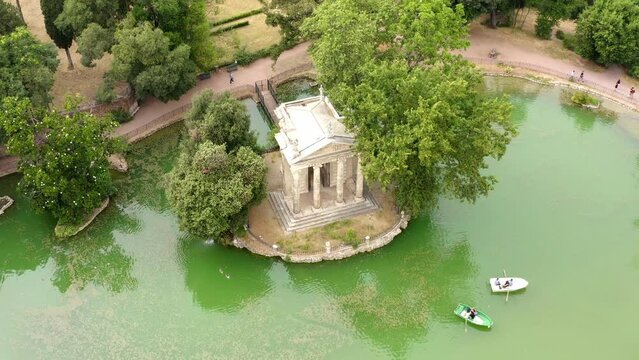 Aerial view of the small lake in Villa Borghese park. This pond is located in Rome, Italy. There are the Temple of Aesculapius and small row boats with people.