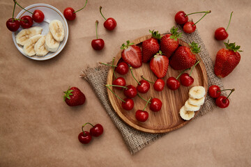 Fototapeta na wymiar Fresh summer fruits - strawberry, banana and cherry flat lay. Summer vitamins, healthy food.