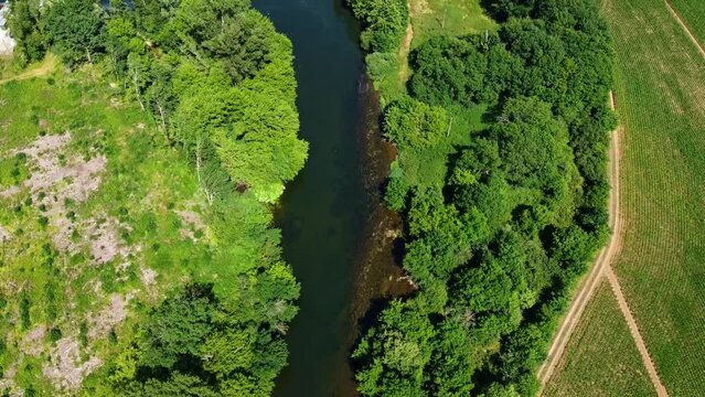 Cours d&rsquo;eau poss&eacute;dant un barrage. Diverses activit&eacute;s humaines aux alentours dont l&rsquo;agriculture. Rivi&egrave;re sinueuse vue en drone.