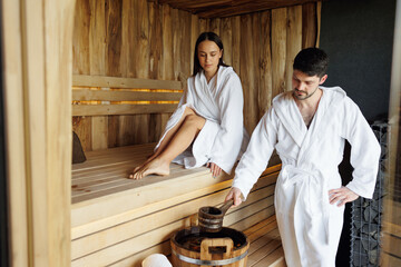 Young man and woman relaxing in spa resort sauna