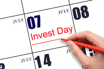 Hand drawing red line and writing the text Invest Day on calendar date July 7. Business and financial concept.