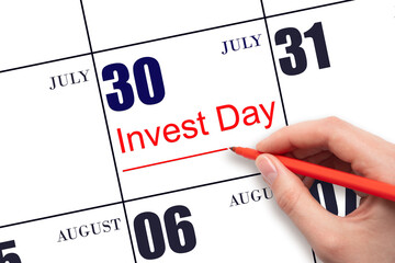 Hand drawing red line and writing the text Invest Day on calendar date July 30. Business and...