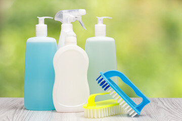 Bottles of dishwashing liquid, brushes on natural background.