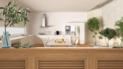 Wooden table top, cabinet, panel or shelf with shutters close up. Olive branch in vase and candles. Blurred background with modern white and wooden kitchen, interior design
