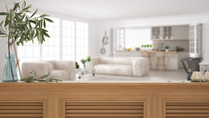 Wooden table top, cabinet, panel or shelf with shutters close up. Olive branch in vase and candles. Blurred background with white scandinavian kitchen and living room, interior design