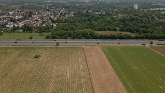 Static aerial time lapse of numerous cars driving along a freeway between fields and a village in Hesse, Germany