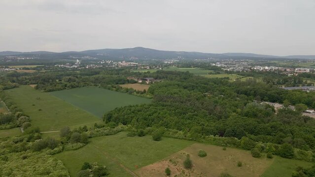 Approaching flight towards an abandoned military airfield within forests and fields in Eschborn, Germany. Wide angle aerial footage