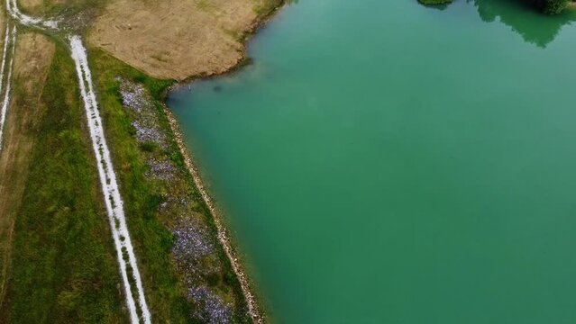 Retenue d'eau vue du ciel avec son chemin la traversant de part et d'autres et son lac. Digue form&eacute;e de v&eacute;g&eacute;tation retenant l'eau du lac.
