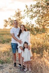 Fototapeta premium Happy parents walk with their daughter among meadow.