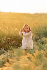 Fototapeta na wymiar Little child girl walks among meadow.