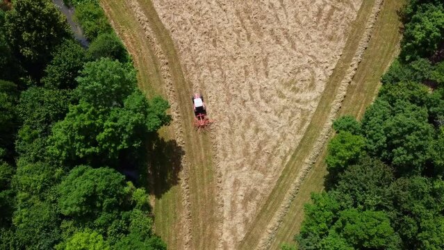 Tracteur travaillant dans un environnement rural et paisible au milieu de la biodiversit&eacute;. Cr&eacute;ation de petits monticules de foins vu du ciel.