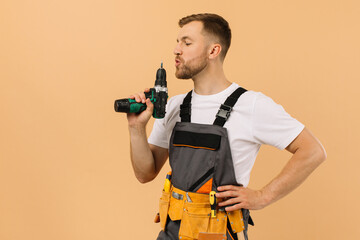 Fototapeta na wymiar Positive male repairman at home with screwdriver on beige background