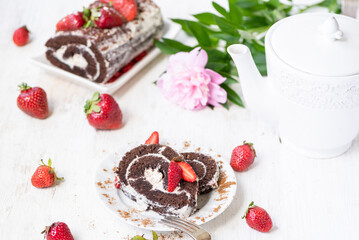 Appetizing slices of chocolate roll with strawberries on the festive table