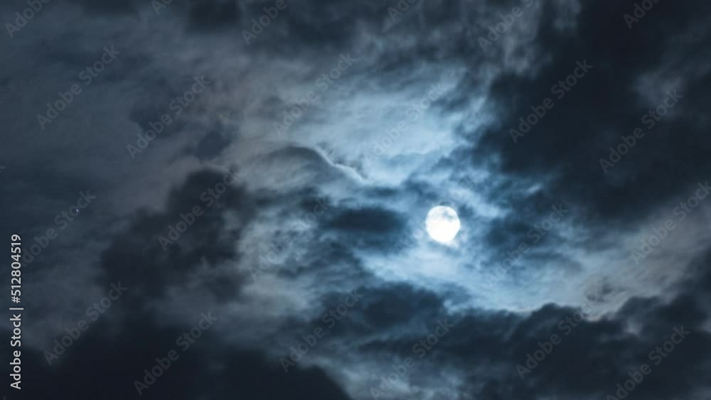 Wall mural full moon with moving black clouds. nighttime timelapse. clouds floating through the bright disk of 