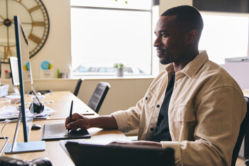 Young Black Male Advertising Marketing Or Design Creative In Office Sitting At Desk Working On Computer