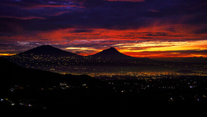 Sky at dawn with the city lights still on. Seen the silhouette of the mountain. The sky is cloudy. Magelang City, Central Java, Indonesia           