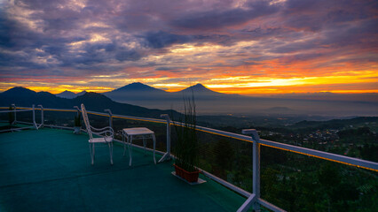 Terrace with view of nature and mountains at sunrise. There are mount Andong, Telomoyo, Merbabu and Merapi Volcano. The sky is cloudy. This place named Wanamukti Siguede, Magelang, Indonesia