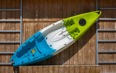 A plastic  colorful kayak hung on a wooden wall