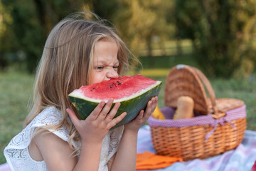 portrait of pretty little girl is having fun while eating a slice of watermelon
