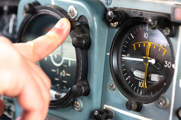 Close-up of an aviator's hand in soft focus presses the button of the aviation horizon instrument on the dashboard of the aircraft. Pilot labor concept.