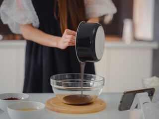 bakery, food and people concept. Beautiful woman cook chocolate cake in kitchen room. Young woman smiling, loves to cook in a beautiful modern kitchen.
